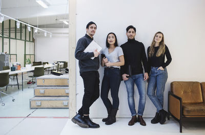 Full length portrait of confident entrepreneurs standing in creative office