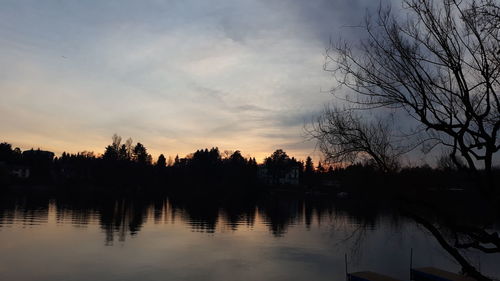 Silhouette trees by lake against sky during sunset