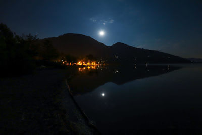 Scenic view of illuminated mountains by lake against sky at night