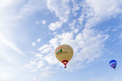 Low angle view of hot air balloons flying against sky