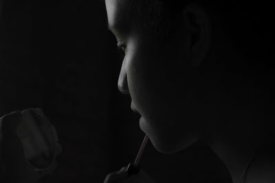 Close-up of teenage boy against black background