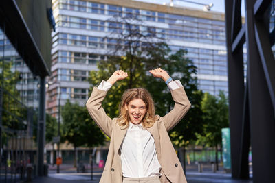 Portrait of young woman standing in city