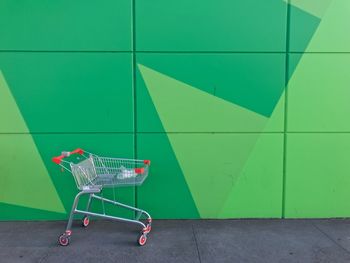 Shopping cart against green wall