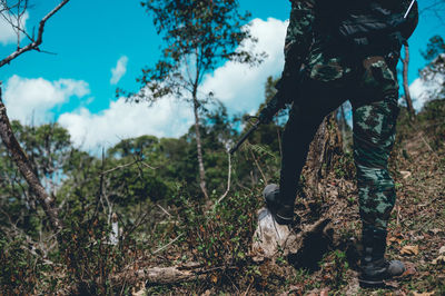 Low section of soldier standing by plants against sky