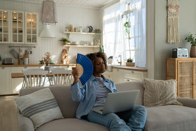 Young woman sitting on sofa at home