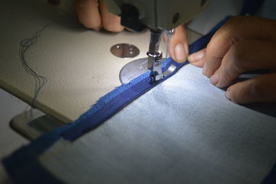 Close-up of hands working on sewing machine