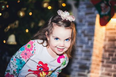 Happy toddler flashing a smile in front of christmas tree and fireplace