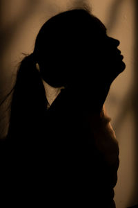 Close-up portrait of silhouette woman against wall