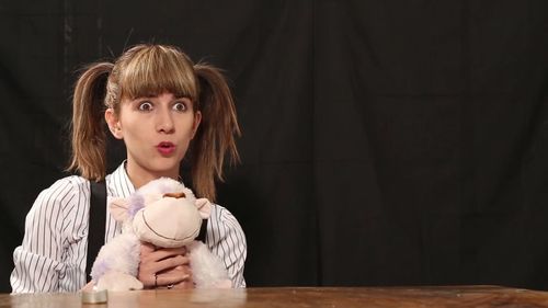 Close-up of surprised young woman with stuffed toy looking away