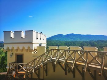 Building by mountains against clear blue sky