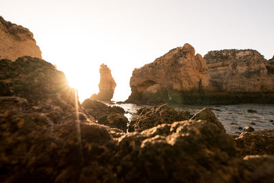 Rock formations in sea against clear sky