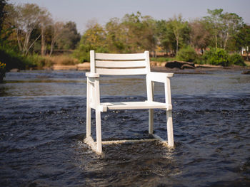 Empty chair on shore by lake