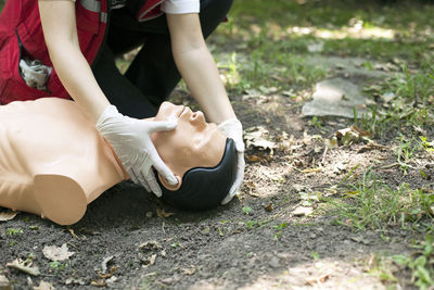 Low section of woman practicing on cpr dummy at field