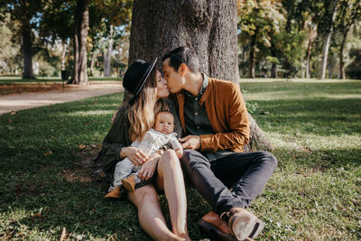 Full length of mother and daughter on grass against trees