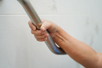 Close-up of hand holding paper against wall