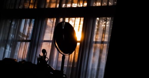 Silhouette man standing by window