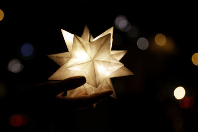 Person holding illuminated lights at night