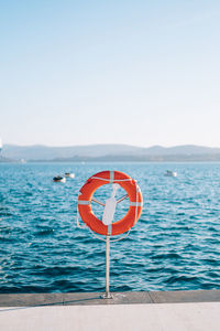 Information sign by swimming pool against sea against clear sky