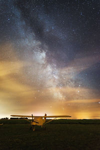 Airplane on field against sky at dusk