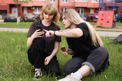Side view of friends using mobile phone