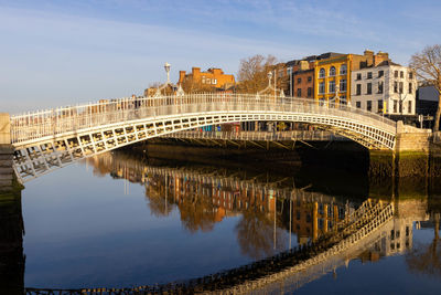 Arch bridge over river against sky in city