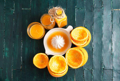 Still life on a green wooden base of an orange squeezer with orange ju