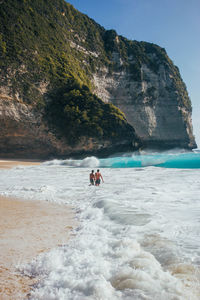 People on beach by mountain against sky