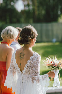 Woman holding bouquet of people in front of building