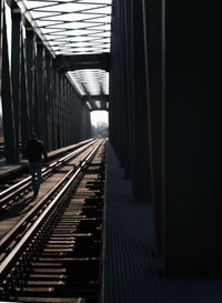 Rear view of man walking on railroad track