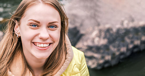 Portrait of young attractive blue-eyed woman looking at camera and smiling in yellow jacket person