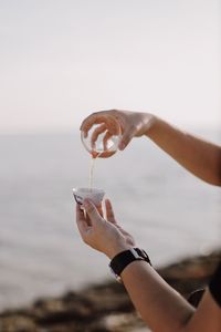 Close-up of hand holding water against sky