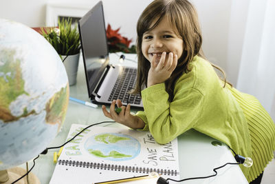 Portrait of smiling girl by laptop and book