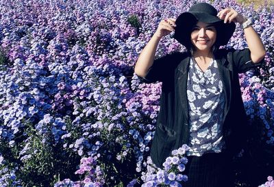 Portrait of woman standing amidst purple flowering plants