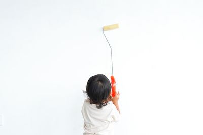 Rear view of woman holding figurine against white background