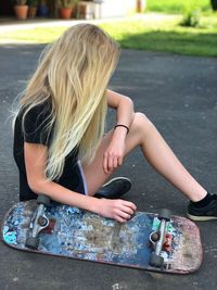 Midsection of woman sitting on skateboard in city