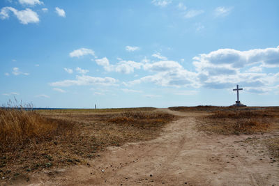 Dirt road on land against sky