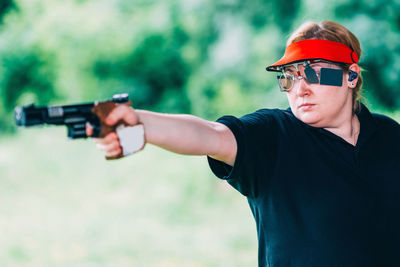 Close-up of woman aiming gun outdoors