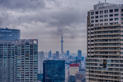 Skyscrapers in city against cloudy sky