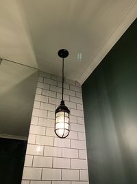 Low angle view of illuminated light bulb hanging on wall