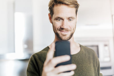 Portrait of smiling man looking at cell phone