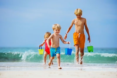 Rear view of shirtless boy playing at beach