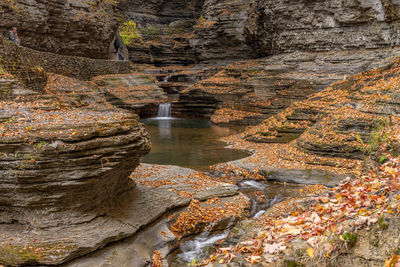 Waterfalls in a sculpted rocky gorge in the autumn with a stone wall and walking path