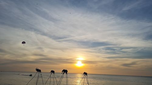 People on beach against sky during sunset