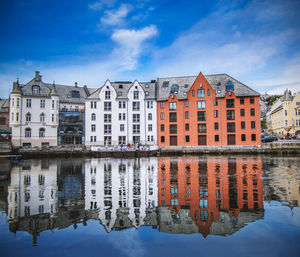 Buildings by river against sky