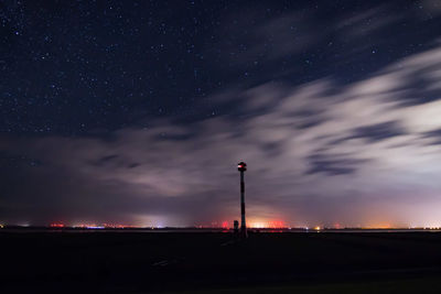 Low angle view of silhouette factory against sky at night