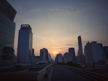 Skyscrapers in city against sky at sunset