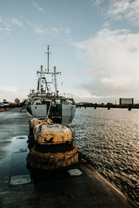 Sailboat moored at harbor against sky