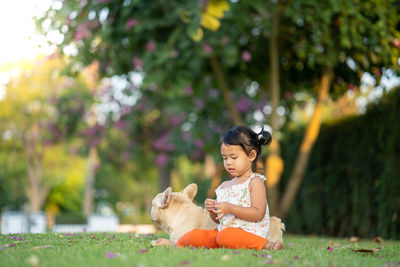 Cute girl with dog sitting at park