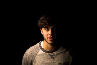 Portrait of young man against black background