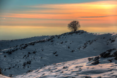 Scenic view of snow against sky at sunset